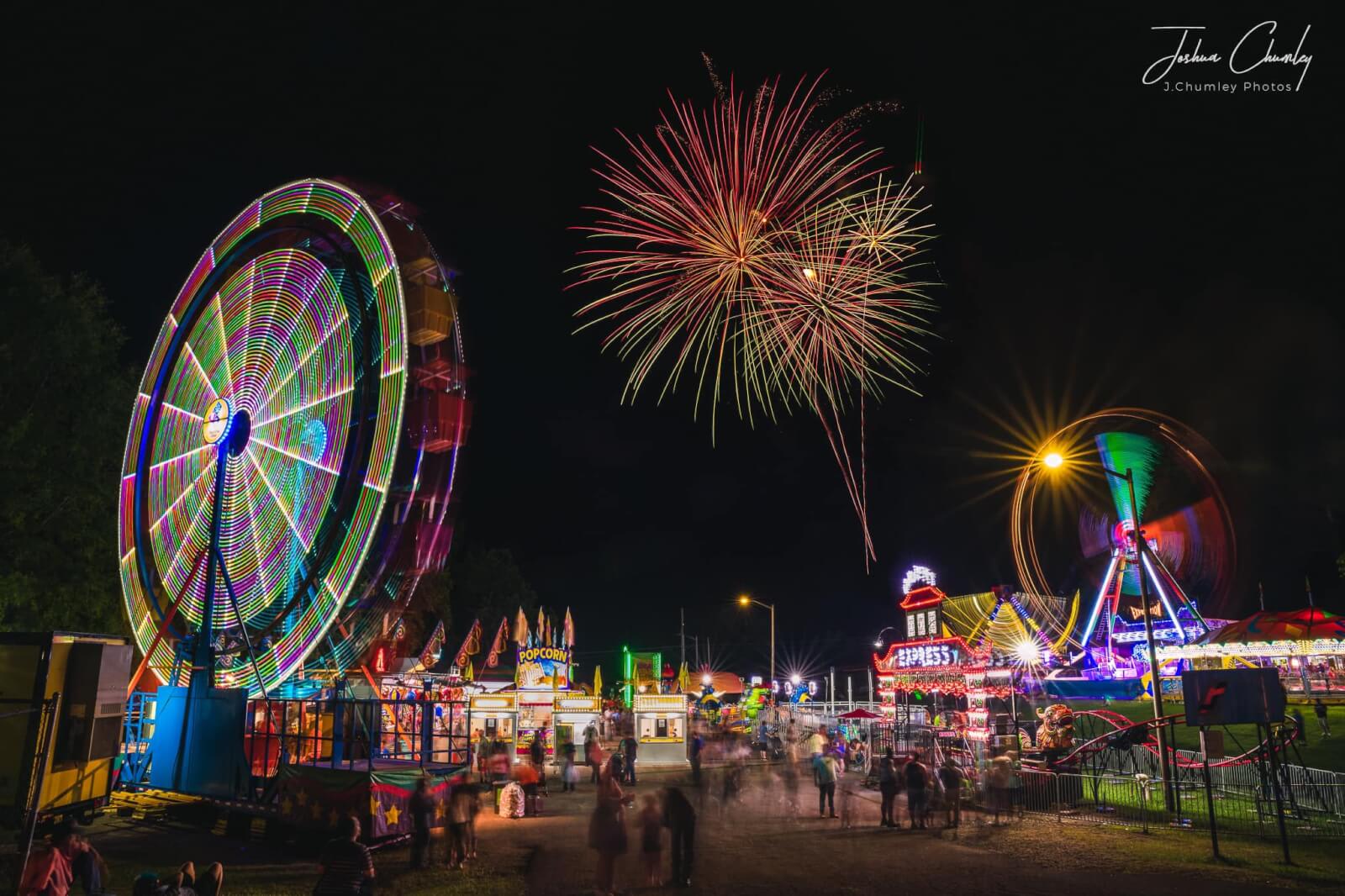 A vibrant nighttime carnival scene with colorful rides, bright lights, and fireworks in the sky in Atlanta, Georgia.
