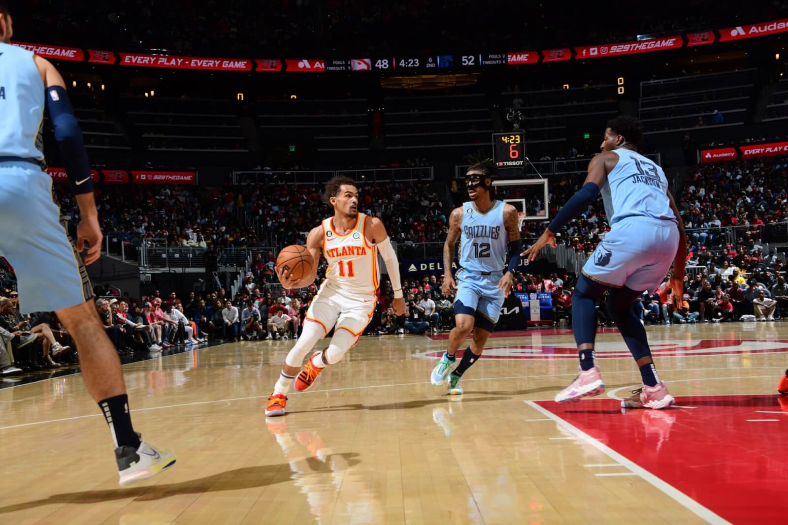 NBA basketball player in white and orange uniform dribbling ball down court in Atlanta, Georgia.