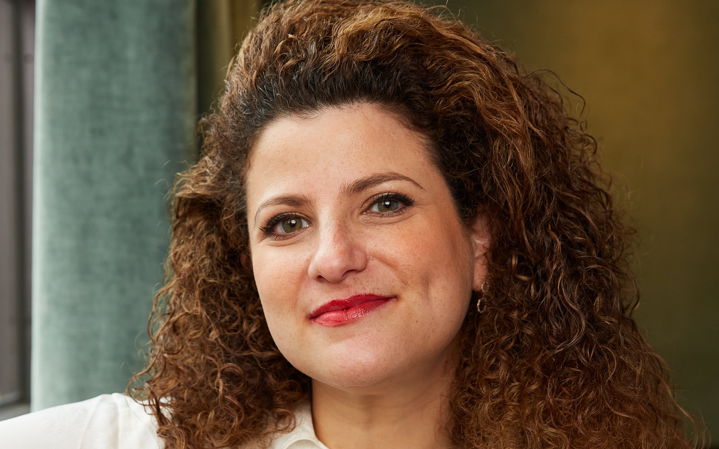A smiling woman with long, curly brown hair and red lipstick in Atlanta, Georgia.