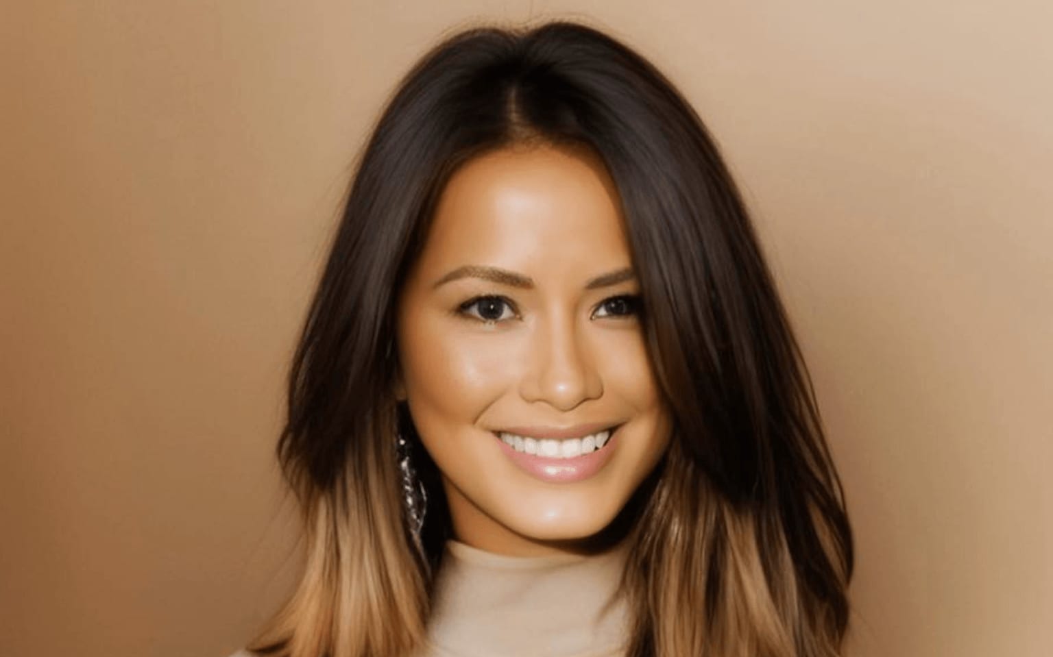 A smiling woman with long, dark hair and a beige turtleneck sweater in Atlanta, Georgia.