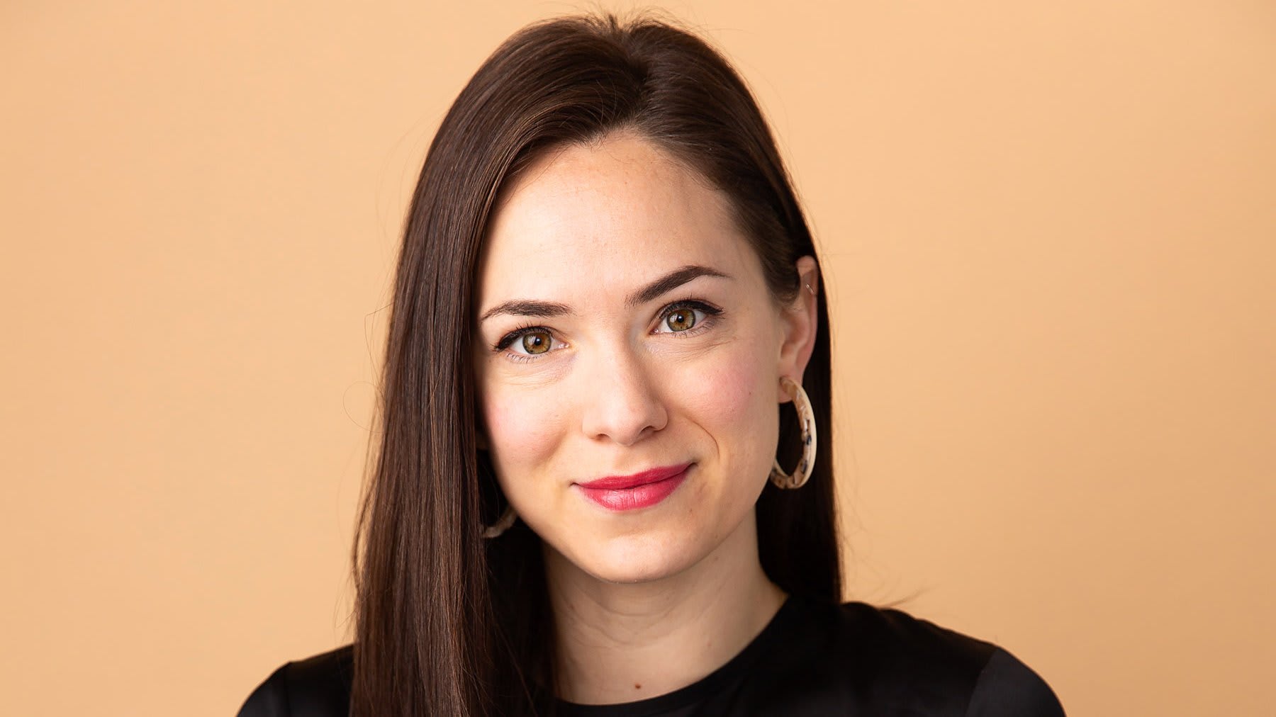 A smiling woman with long dark hair and red lipstick against a beige background in Atlanta, Georgia.