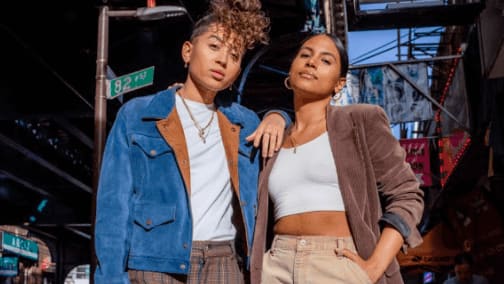 Two women pose together in stylish outfits against an urban backdrop in Atlanta, Georgia.