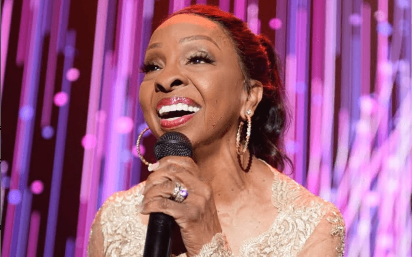 An African American woman with a radiant smile sings into a microphone, adorned in a golden dress in Atlanta, Georgia.