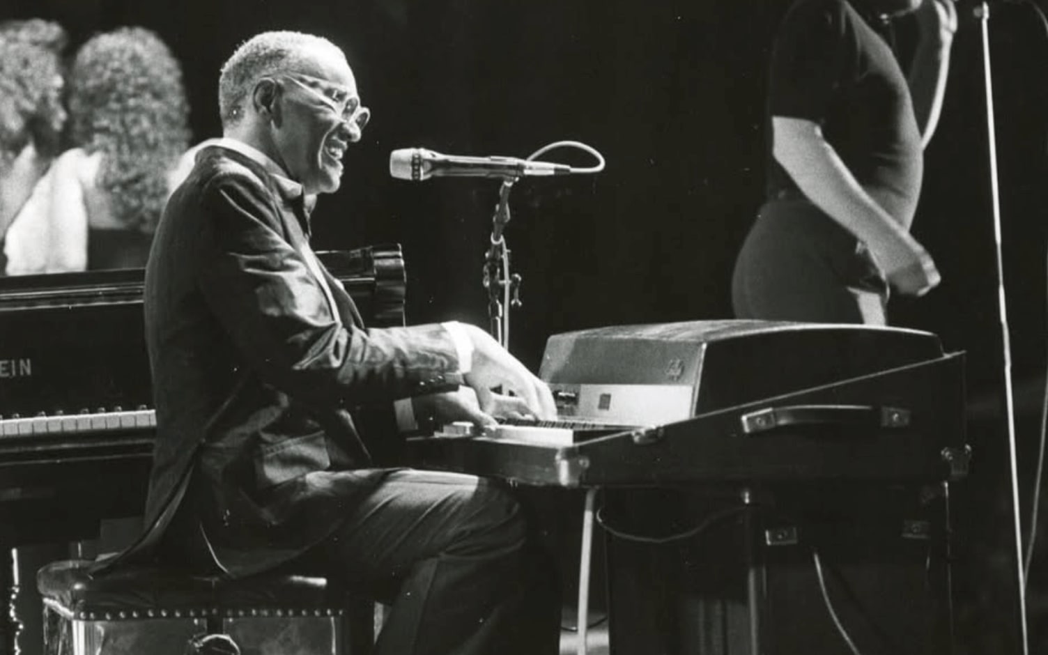 An elderly man in a suit plays a keyboard on stage with a microphone nearby in Atlanta, Georgia.