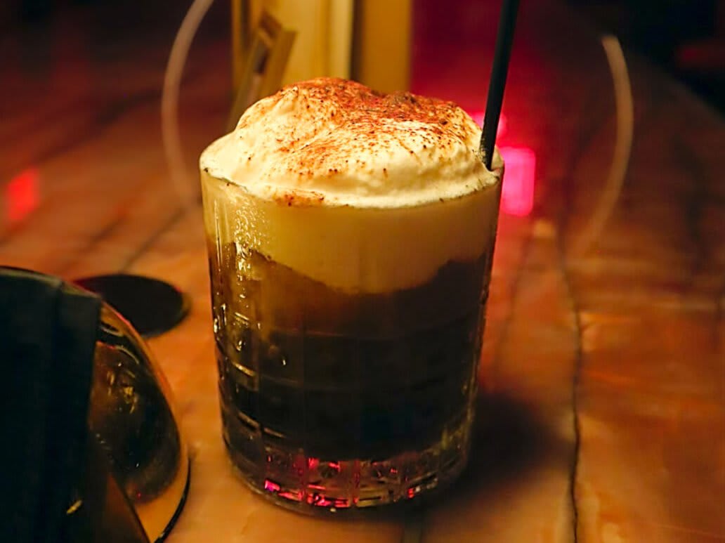 A glass filled with a layered drink, topped with whipped cream and cocoa powder in Atlanta, Georgia.