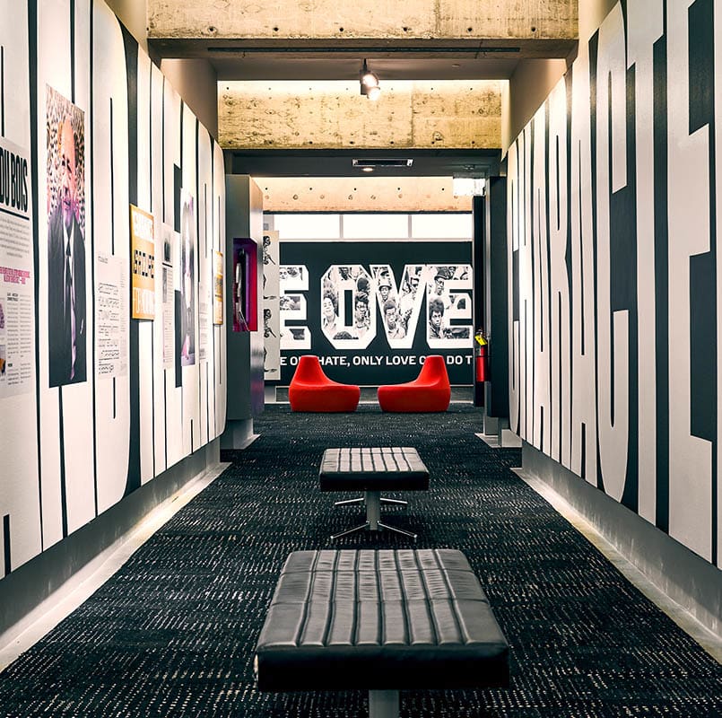 A modern hallway with bold black and white walls, featuring inspirational quotes and artwork, leading to a red 'LOVE' sign at the end in Atlanta, Georgia.