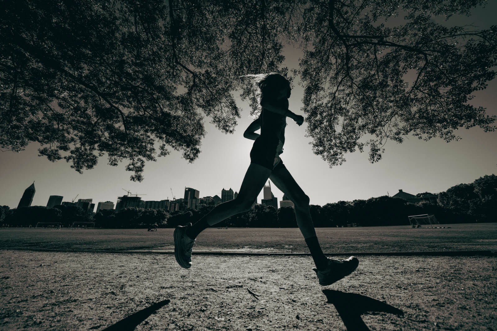 A silhouette of a runner in motion, captured mid-stride under a tree canopy in Atlanta, Georgia.