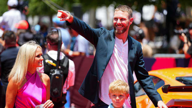 A smiling family of three waves to the crowd at a public event in Atlanta, Georgia.