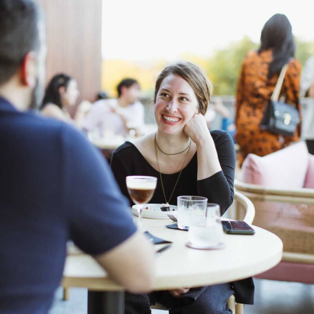 A couple enjoys a casual outdoor meal at a restaurant, smiling and chatting over drinks in Atlanta, Georgia.