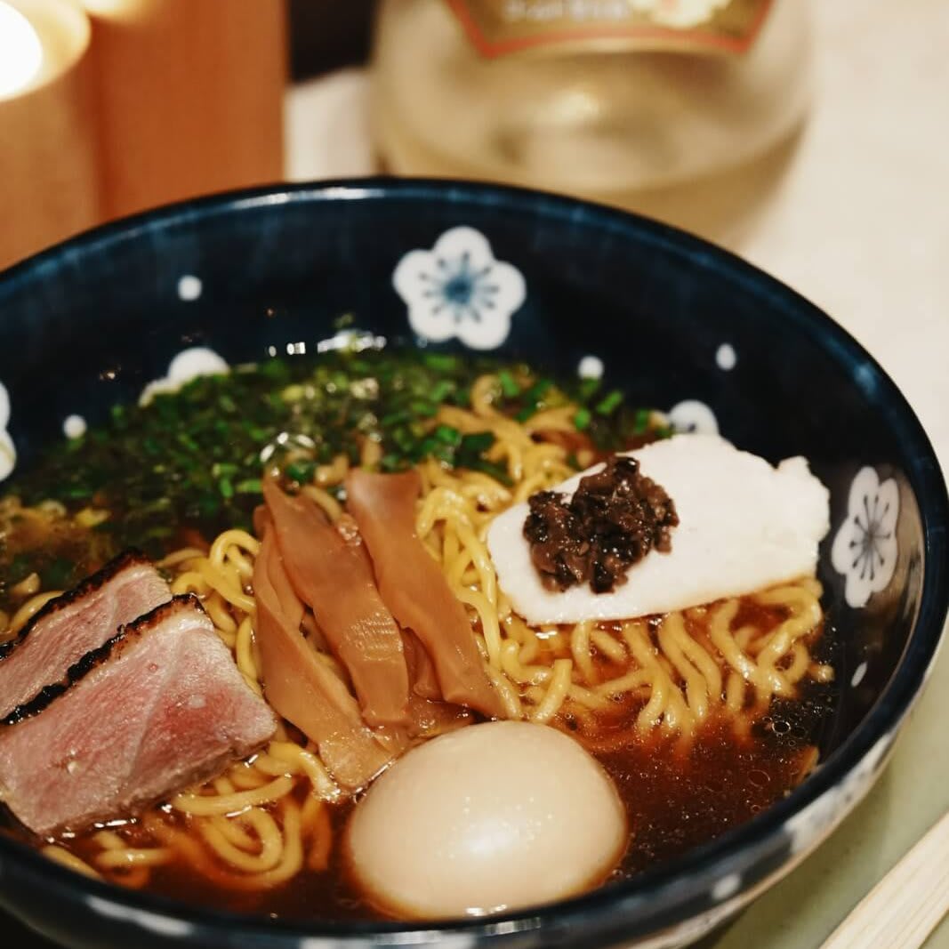 A steaming bowl of ramen with noodles, meat, egg, and vegetables in a dark broth in Atlanta, Georgia.