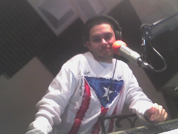 Orlando Rosa 1 A young man wearing headphones and a Puerto Rican flag shirt speaks into a microphone in Atlanta, Georgia.
