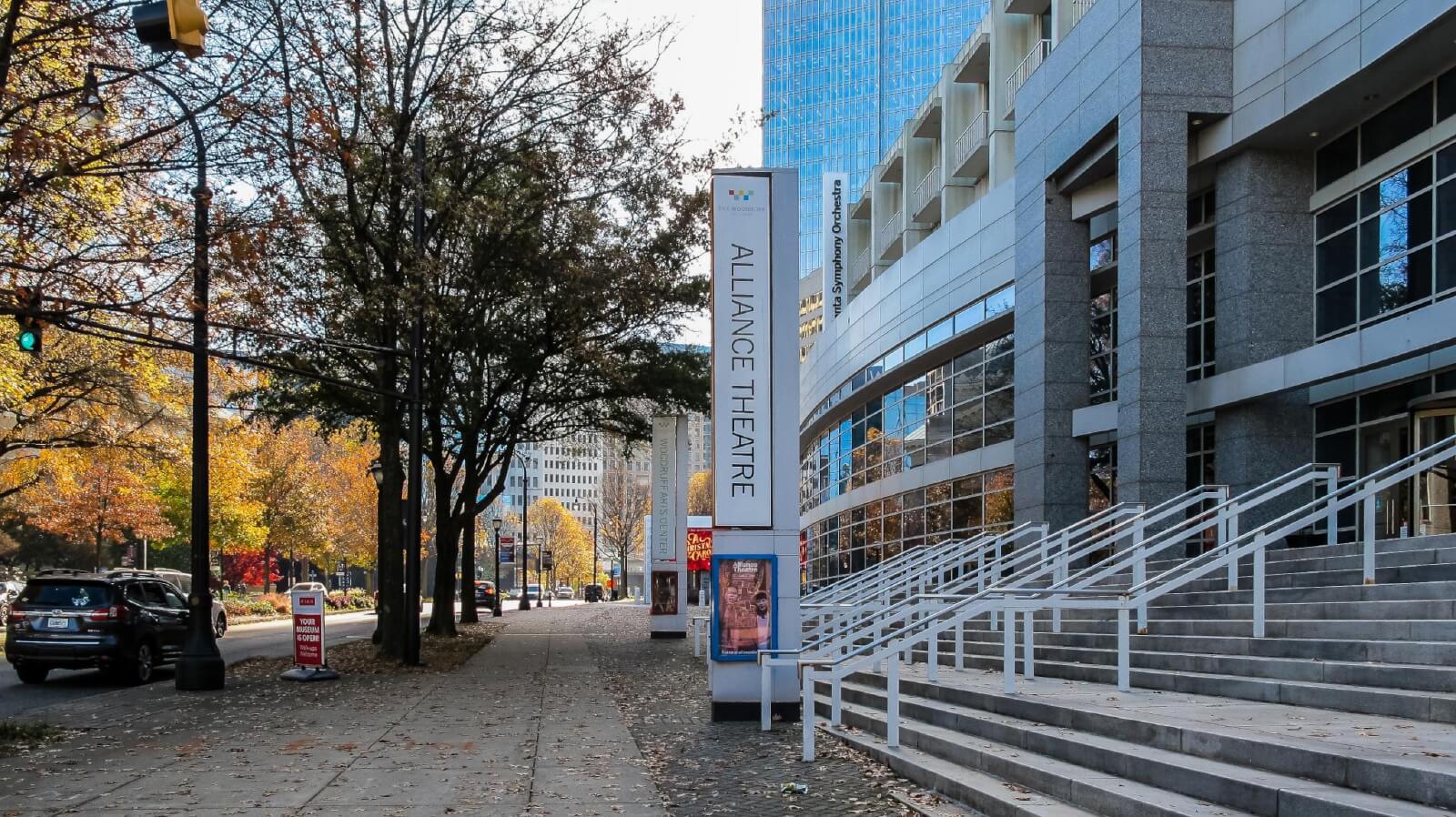 Modern theater entrance with steps, surrounded by autumn trees and city buildings in Atlanta, Georgia.