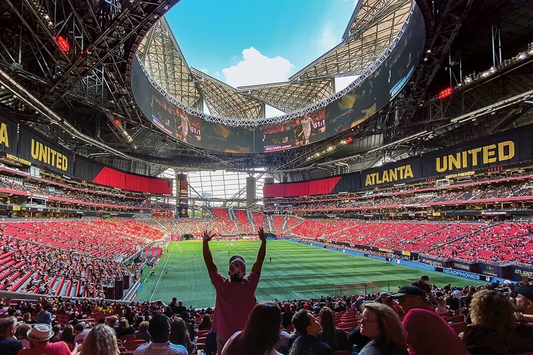 A crowded stadium with a large, open roof and a soccer field below in Atlanta, Georgia.