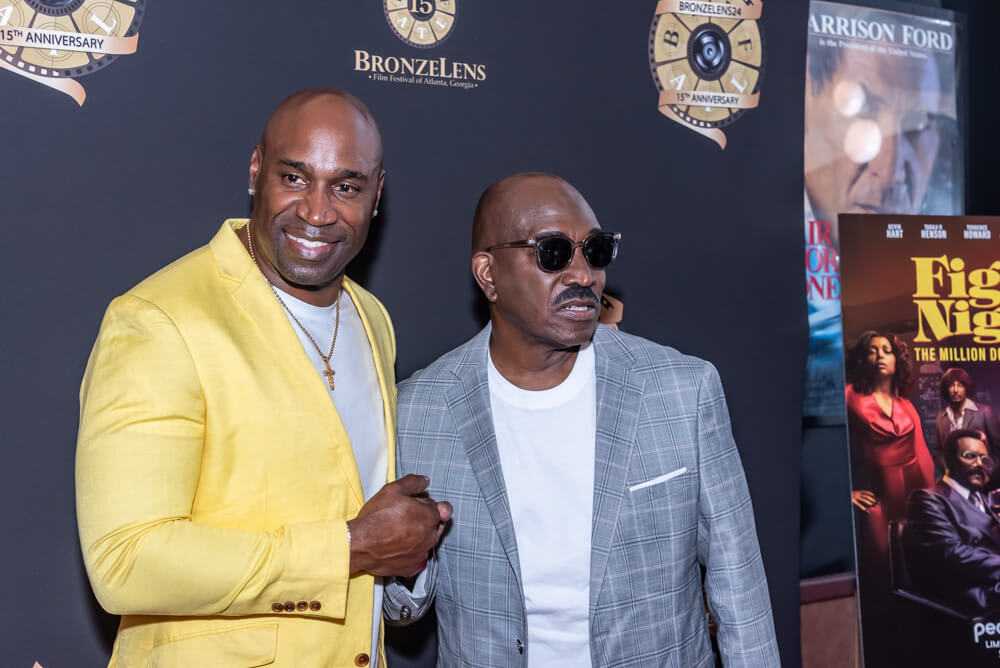 Two men in suits stand together at a movie premiere event in Atlanta, Georgia.