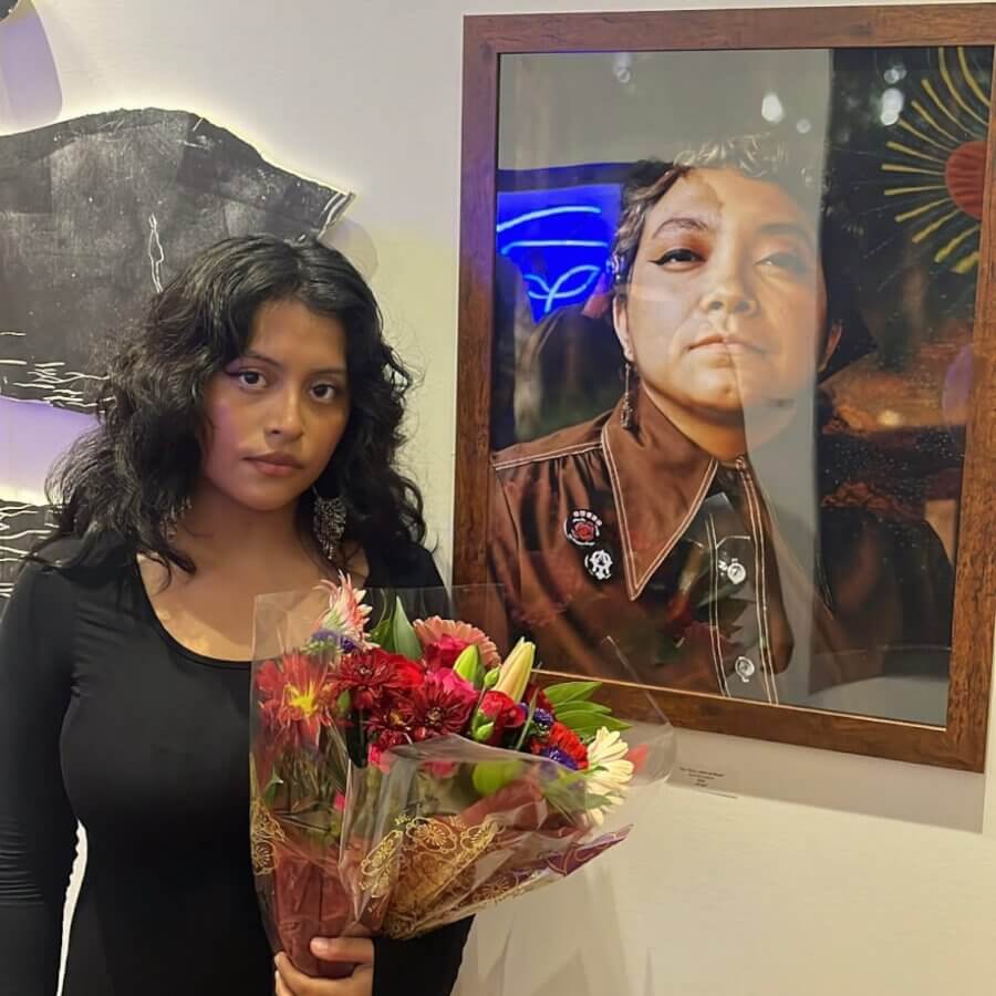 Woman with dark hair holds a bouquet of colorful flowers in front of a framed portrait in Atlanta, Georgia.