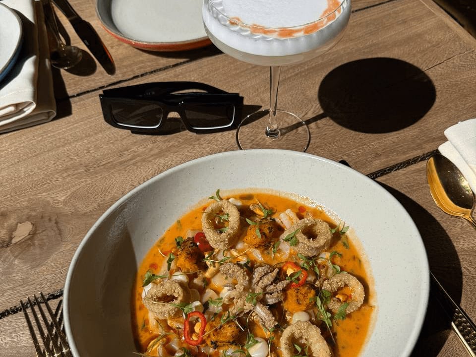 seafood dish on a patio table with a cocktail at madre selva