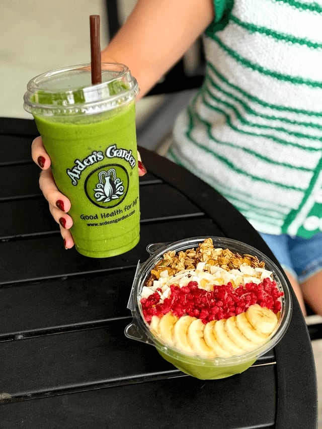 Shop Local in Atlanta 3 A woman holds a green smoothie and a bowl of acai topped with fruit and granola in Atlanta, Georgia.