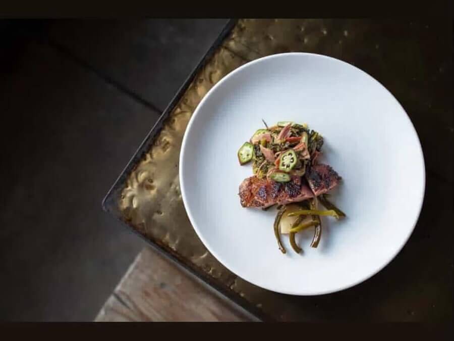 Ultimate Guide to Atlanta’s Pop-Up Restaurants and Supper Clubs 8 A white plate holds grilled meat with a colorful vegetable medley and green beans in Atlanta, Georgia.