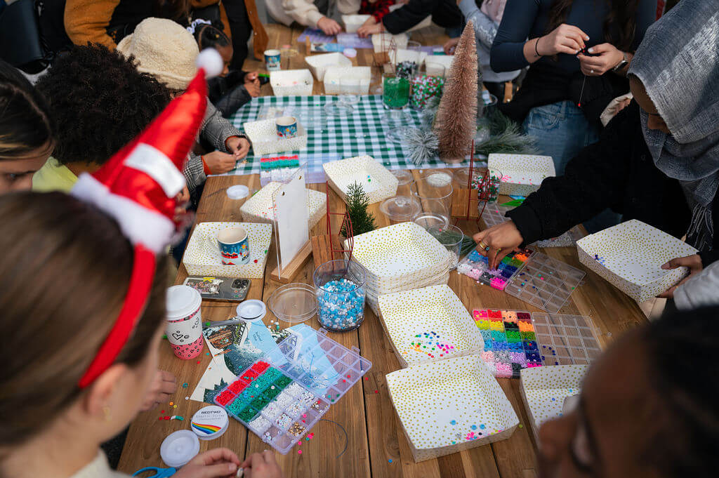 A group of people are gathered around a table, crafting with colorful materials and holiday decorations in Atlanta, Georgia.
