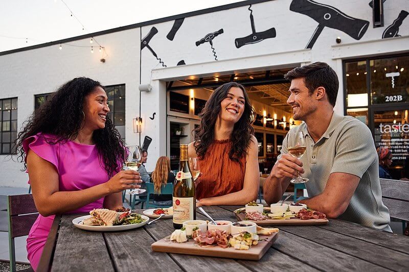 Three friends enjoy wine and charcuterie at an outdoor restaurant table in Atlanta, Georgia.
