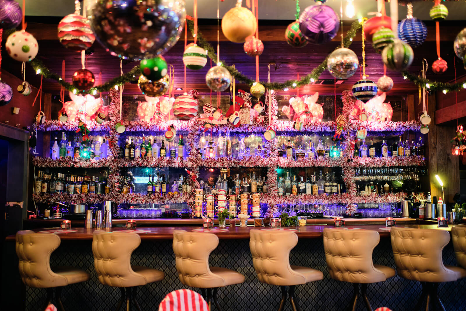 A festive bar with a colorful Christmas tree, hanging ornaments, and a well-stocked liquor shelf in Atlanta, Georgia.