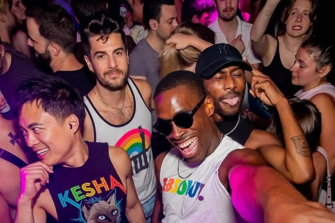 A diverse group of people dancing and celebrating together in a vibrant, colorful club setting in Atlanta, Georgia.