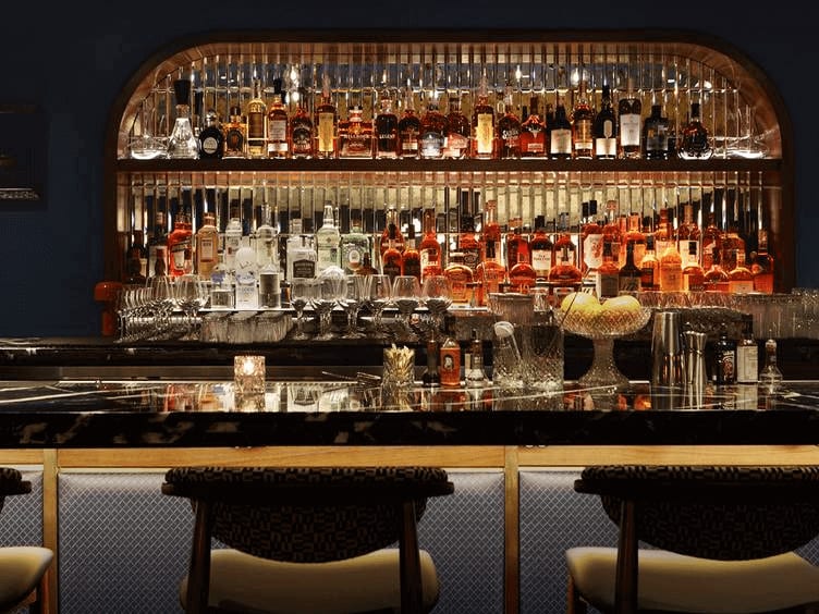 A dimly lit bar with a curved wooden shelf displaying colorful bottles of alcohol in Atlanta, Georgia.