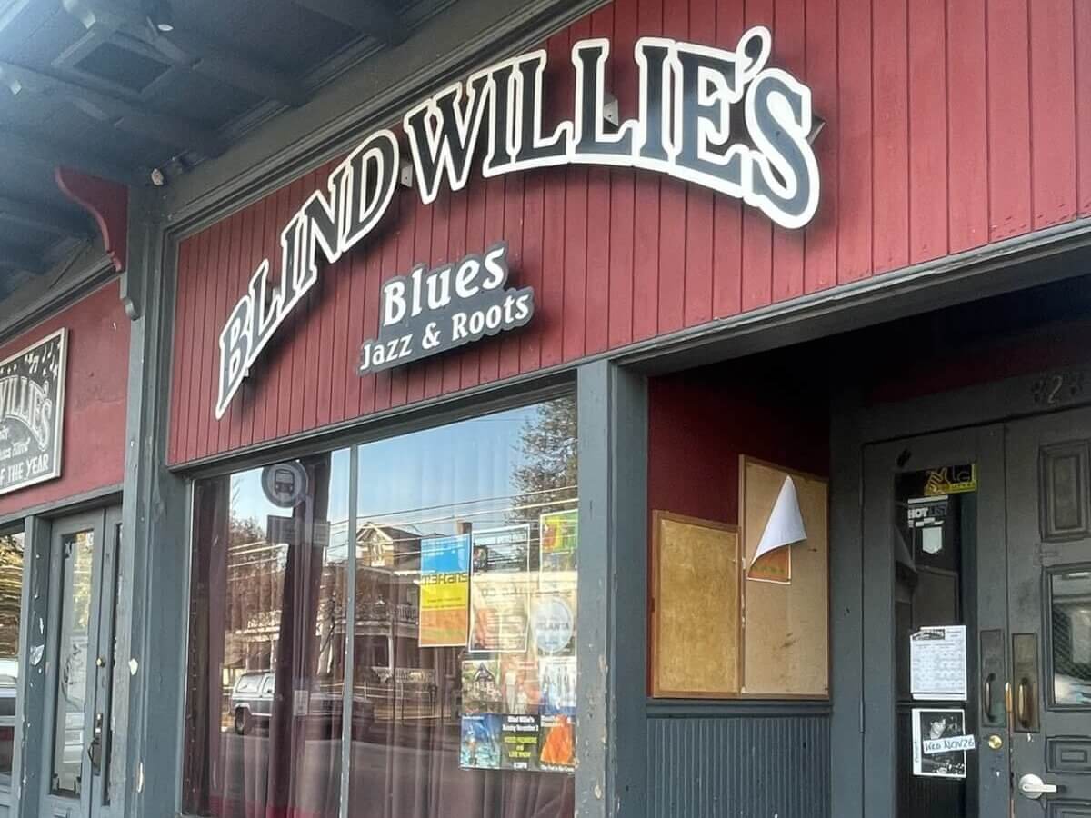 A red and gray storefront with a sign reading 'Blind Willie's Blues Jazz & Roots' and a window display in Atlanta, Georgia.