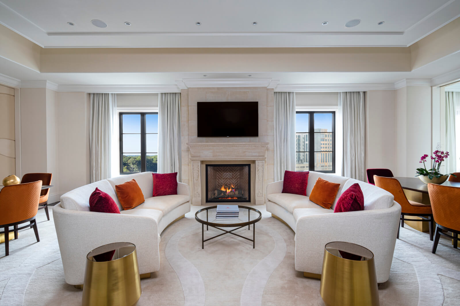 A luxurious living room with a curved white sofa, a fireplace, and a large window overlooking a cityscape in Atlanta, Georgia.