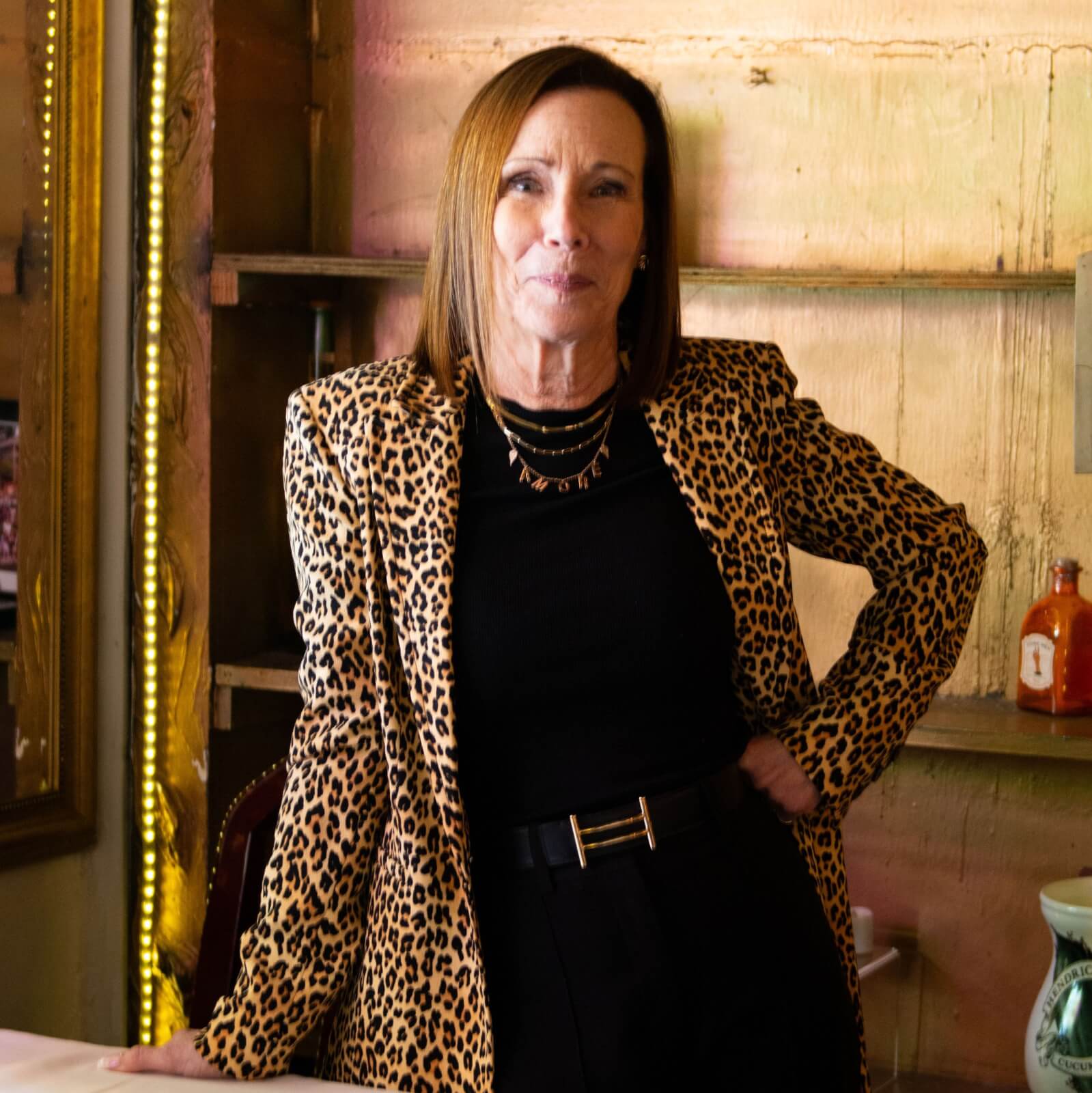 A woman stands confidently in a stylish interior, wearing a bold leopard print blazer over a black outfit, with her hands on her hips in Atlanta, Georgia.