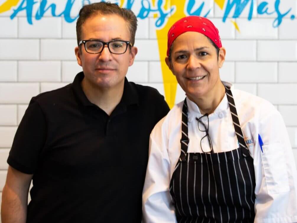 A man and woman stand in front of a colorful mural, one wearing a chef's apron in Atlanta, Georgia.