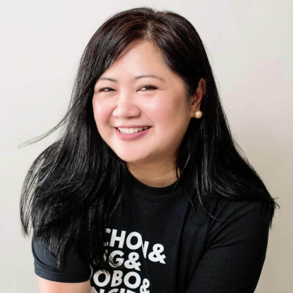 A smiling woman with long black hair wearing a black t-shirt with white text in Atlanta, Georgia.