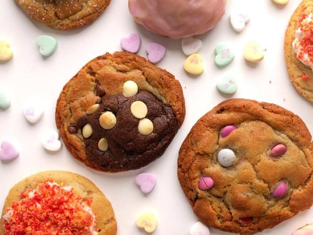 Assorted Valentine's Day-themed cookies with colorful toppings and heart-shaped candies scattered around them in Atlanta, Georgia.