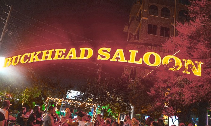 Crowded outdoor event under a large neon sign reading 'Buckhead Saloon' at night in Atlanta, Georgia.
