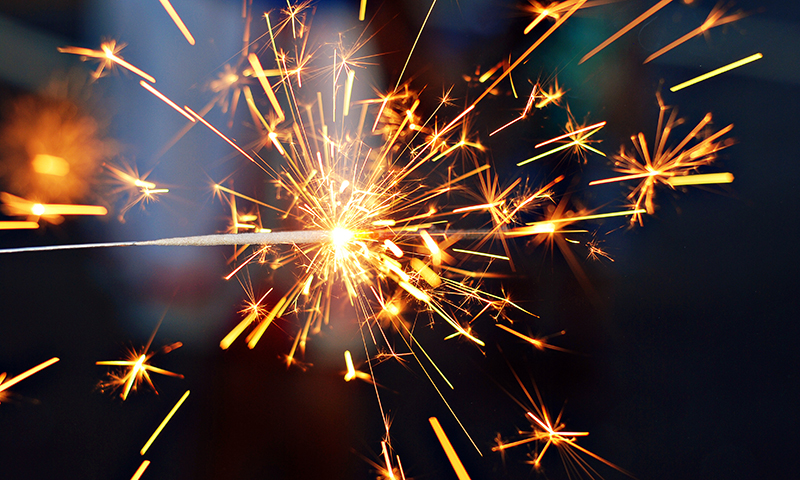 A sparkler explodes in a brilliant display of golden and orange sparks against a dark background in Atlanta, Georgia.
