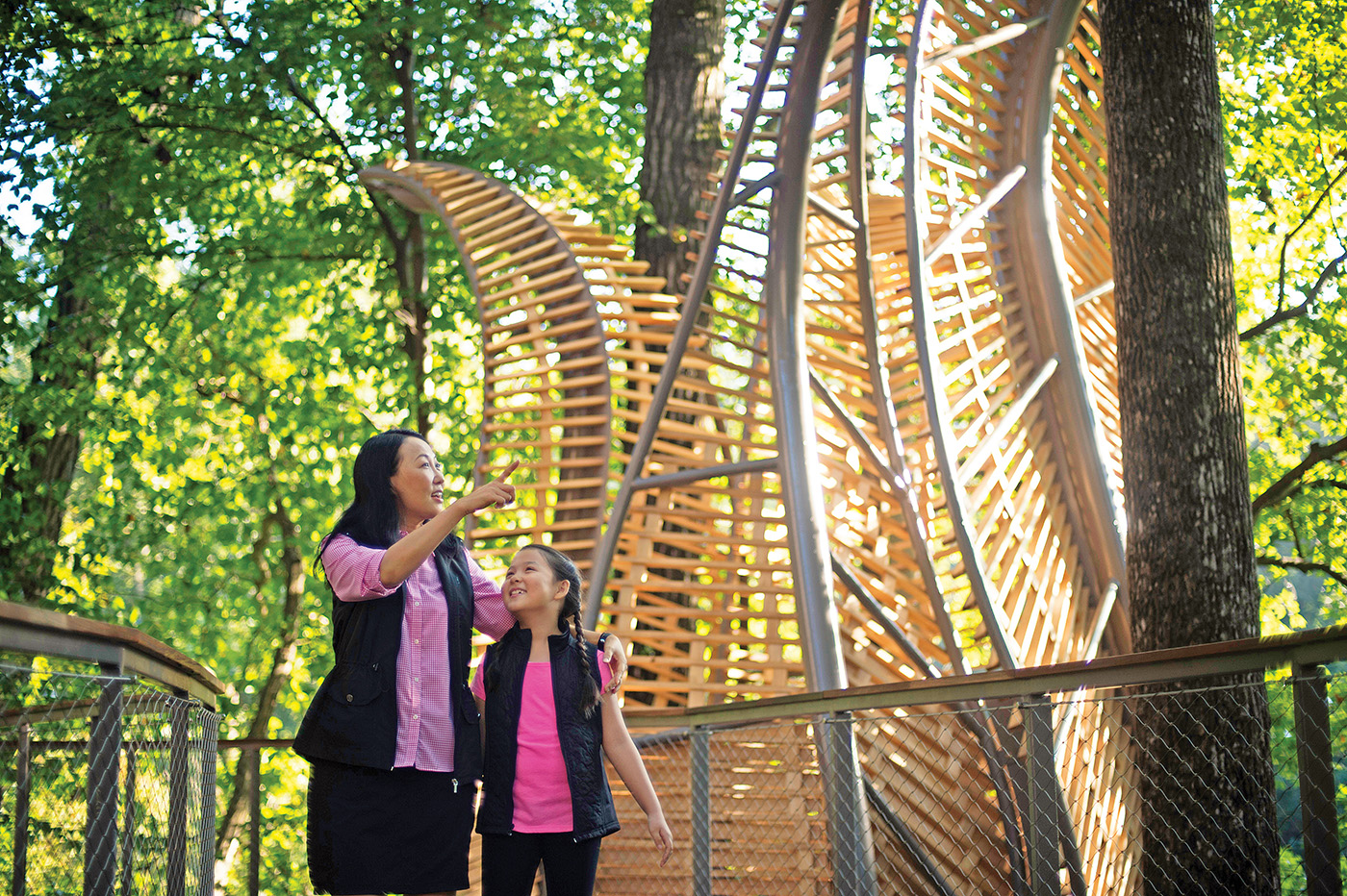 A woman points out something in the trees to a little girl while they explore Fernbank Forest.