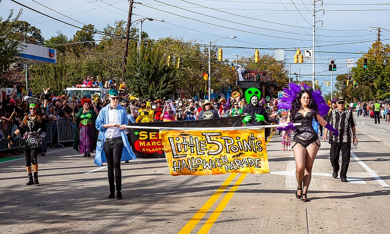 A vibrant Halloween parade featuring costumed participants marching down a city street in Atlanta, Georgia.