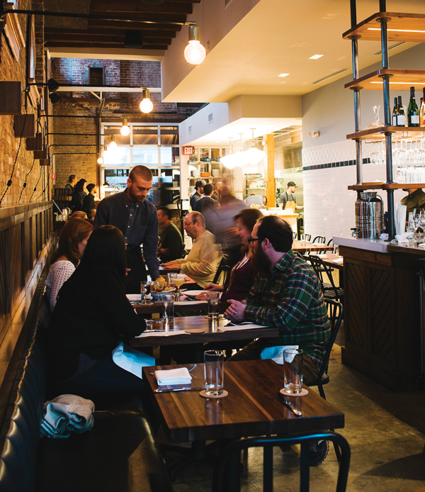 Patrons enjoy a lively dinner at a bustling restaurant with exposed brick walls in Atlanta, Georgia.