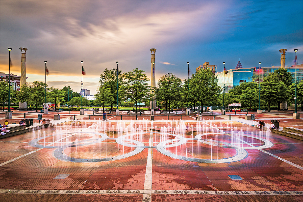Olympic rings fountain in a city plaza with columns and trees in the background in Atlanta, Georgia.
