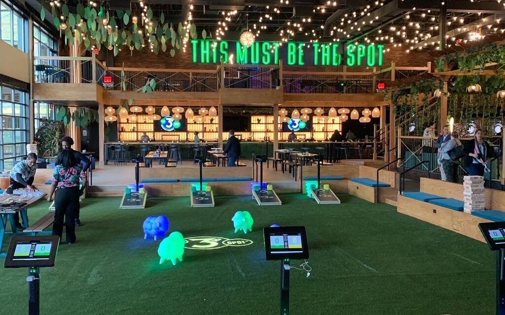 A modern indoor recreational area with games, green turf, and a bar in Atlanta, Georgia.