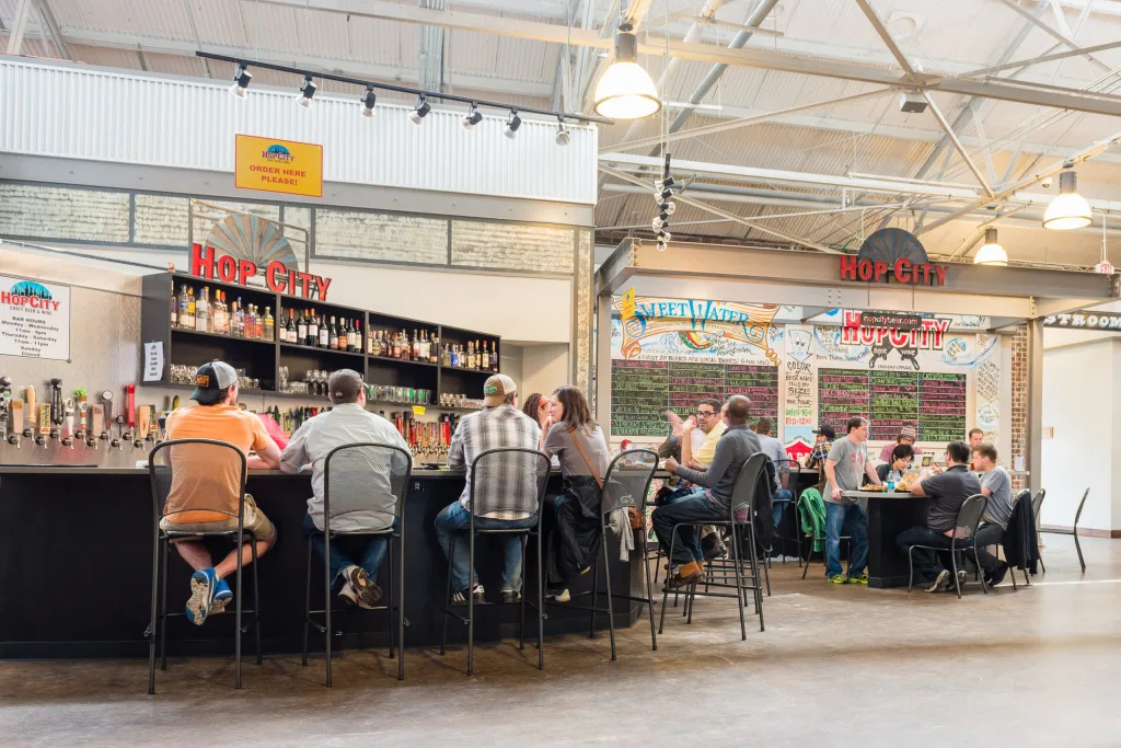 Patrons enjoy a variety of beers at Hop City, a lively brewery and taproom with an industrial aesthetic in Atlanta, Georgia.