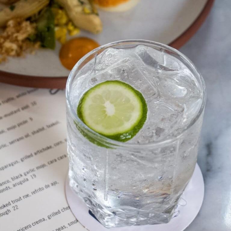 Must-Try Summer Cocktails in Atlanta 7 A refreshing glass of sparkling water with a lime wedge on a marble surface in Atlanta, Georgia.