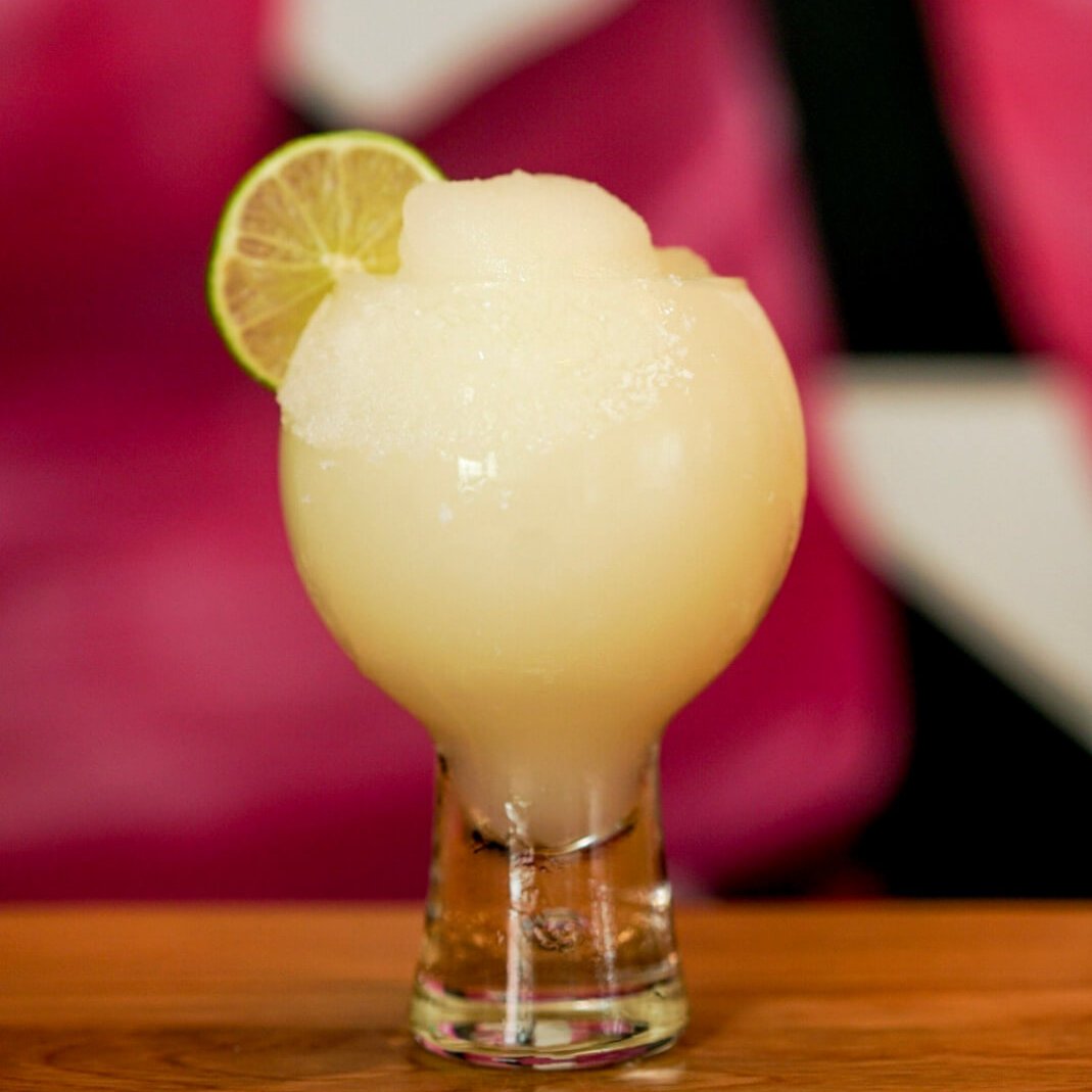 Must-Try Summer Cocktails in Atlanta 10 A frosty margarita glass filled with a creamy yellow cocktail, garnished with a lime wedge in Atlanta, Georgia.