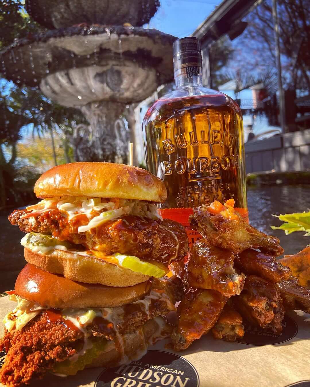 A mouthwatering spread of fried chicken sandwiches and wings with a bottle of Bulleit Bourbon in the background in Atlanta, Georgia.