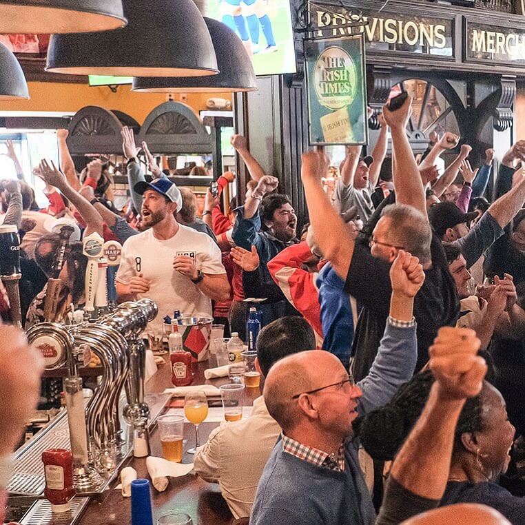 Where to Watch College Football in Atlanta 2 A crowded bar filled with enthusiastic sports fans celebrating a victory in Atlanta, Georgia.