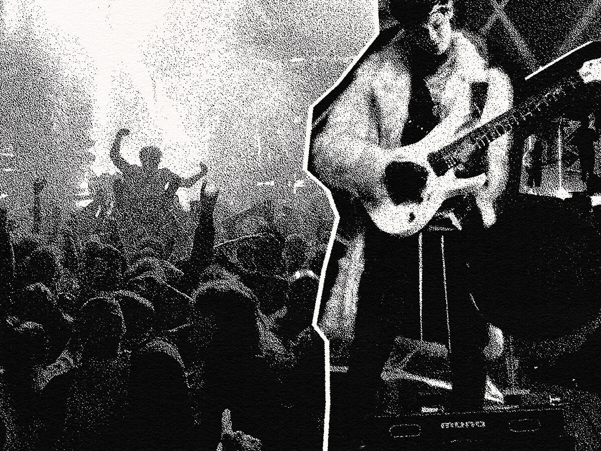 A musician performs on stage, playing an electric guitar amidst a lively crowd at a concert in Atlanta, Georgia.