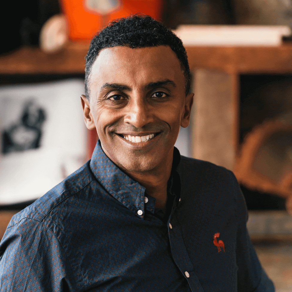 A smiling man wearing a dark blue button-up shirt with a red rooster logo on the chest in Atlanta, Georgia.