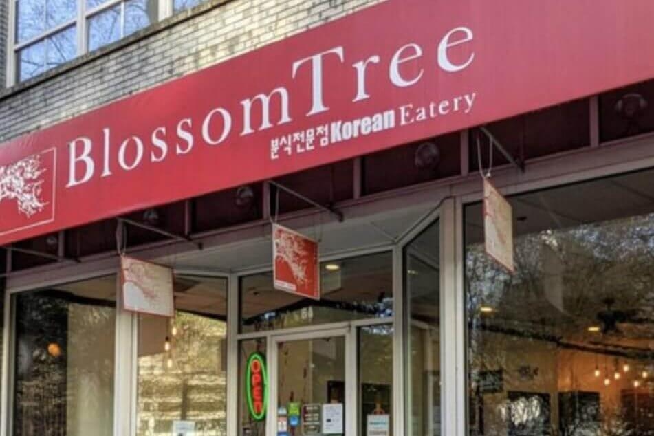 A red-fronted Korean eatery with a tree logo, featuring a glass door and windows in Atlanta, Georgia.