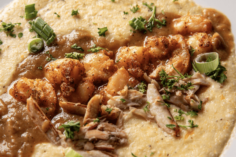 A hearty bowl of shrimp and grits topped with crispy fried shrimp, savory gravy, and fresh herbs in Atlanta, Georgia.