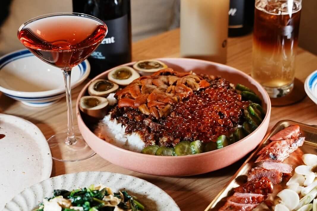 A lavish spread of Asian-inspired dishes, including a colorful rice bowl topped with various meats and vegetables, accompanied by a variety of side dishes, drinks, and a glowing lamp in Atlanta, Georgia.